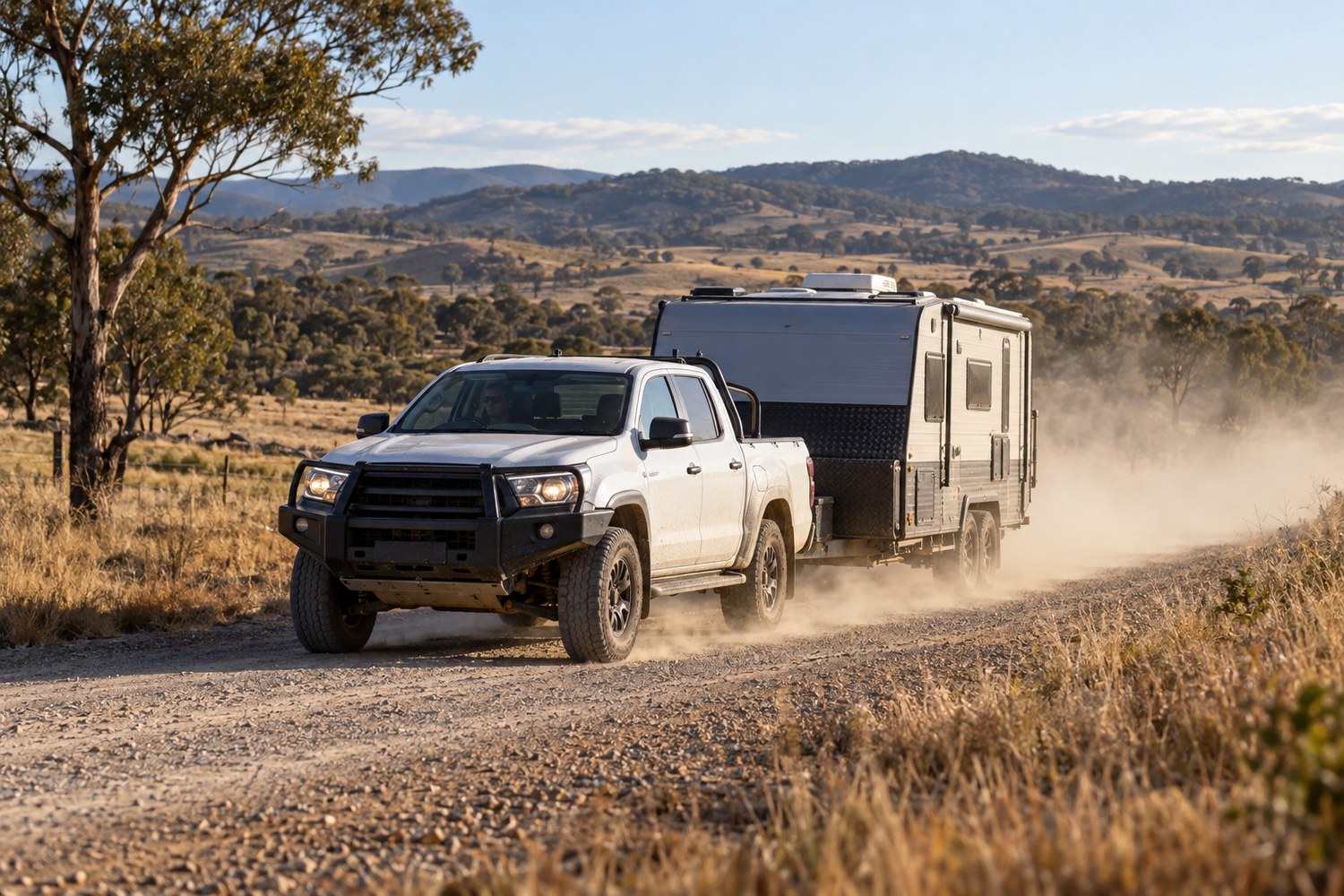 Work ute towing a caravan on a dusty regional road
